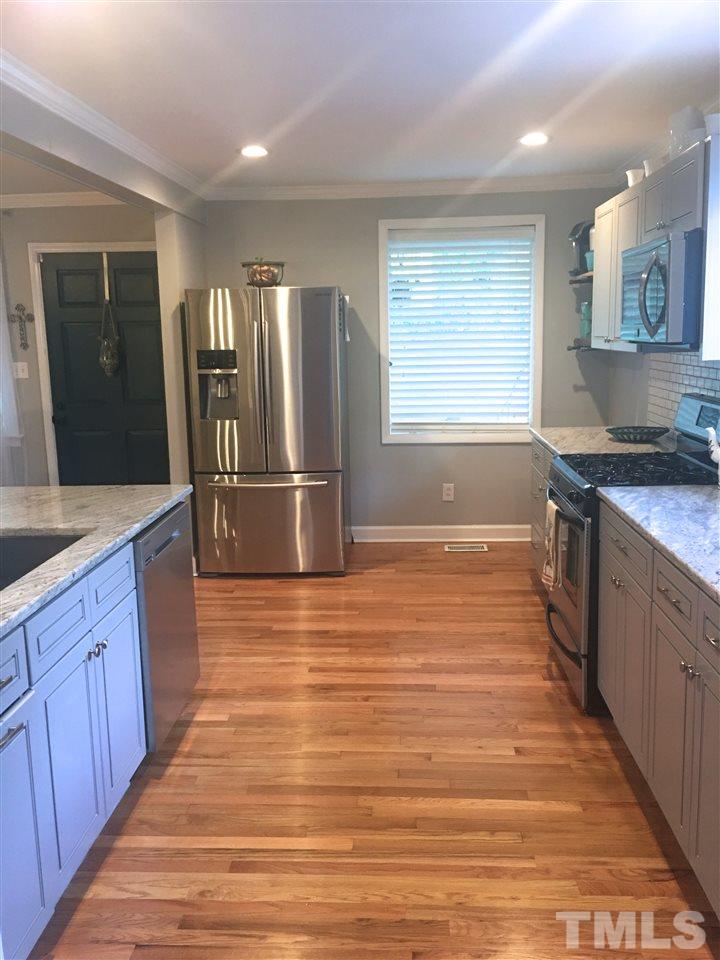 512 Rose Lane Raleigh, NC 27610 - Photo 3 of 22 a large kitchen with stainless steel appliances granite countertop a stove and a wooden cabinets