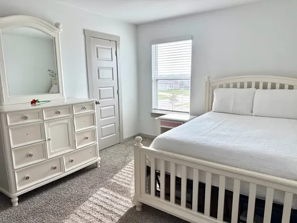 a bedroom with a bed a dresser and a window