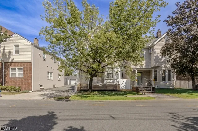 a front view of a house with a garden and trees