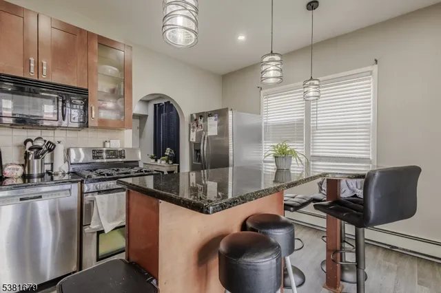 a kitchen with stainless steel appliances granite countertop a stove a sink dishwasher and cabinets with wooden floor