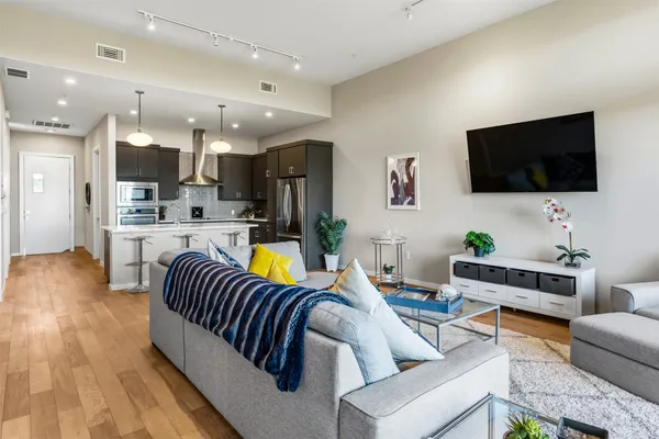 a living room with stainless steel appliances furniture and a view of kitchen