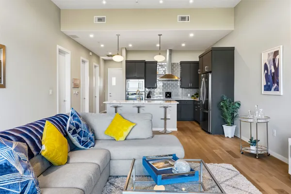 a living room with furniture kitchen view and a chandelier