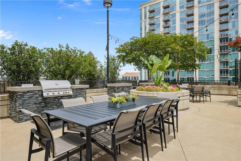 250 Pharr Road Northeast, Unit 606 Atlanta, GA 30305 - Photo 22 of 31 a view of a roof deck with table and chairs couches under an umbrella with potted plants