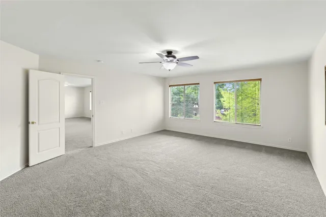 an empty room with windows and chandelier fan