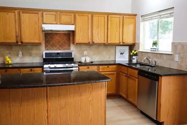 a kitchen with stainless steel appliances granite countertop sink stove top oven and cabinets