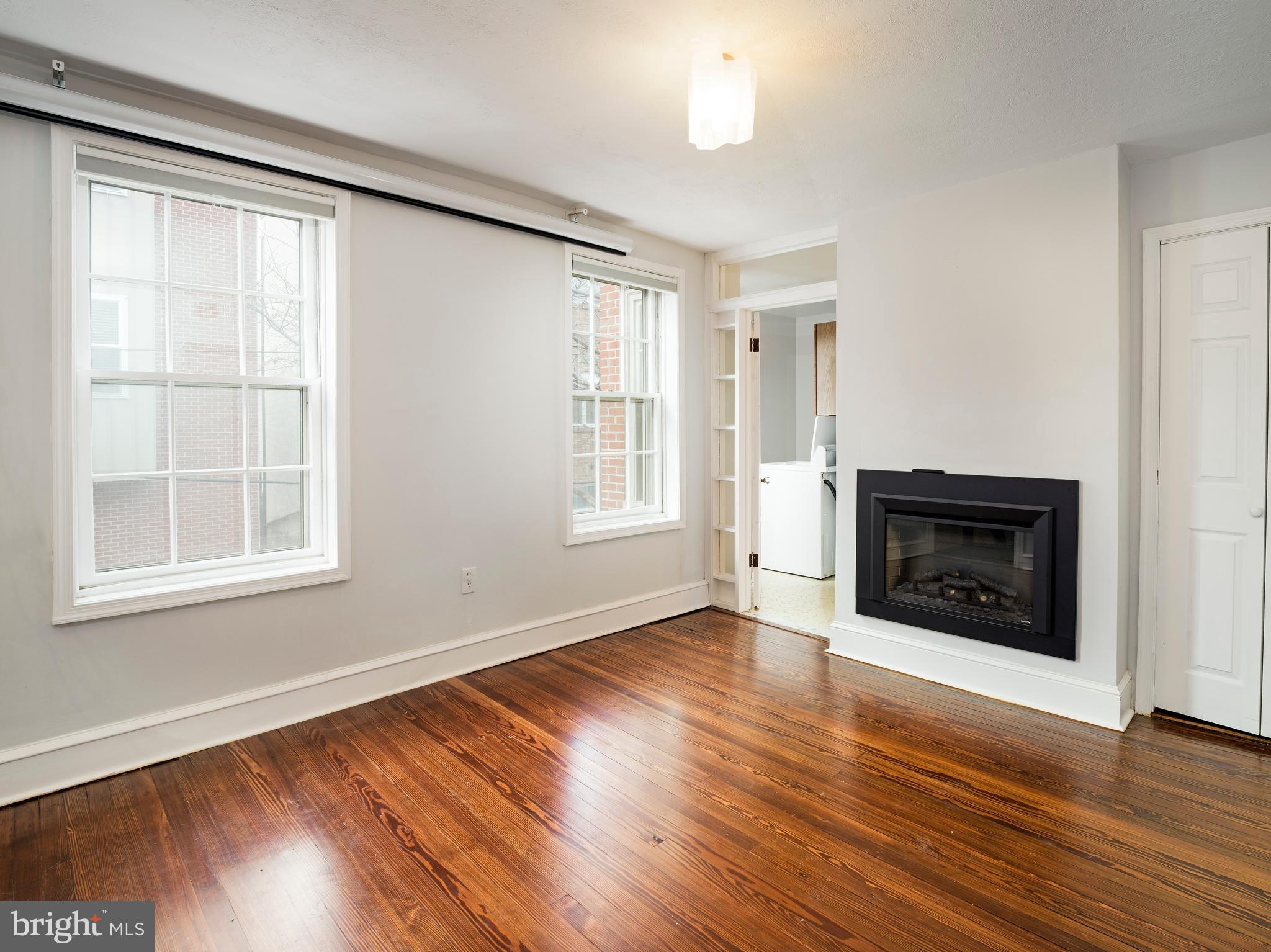 223 Carpenter Street Philadelphia, PA 19147 - Photo 22 of 42 an empty room with wooden floor fire place and windows