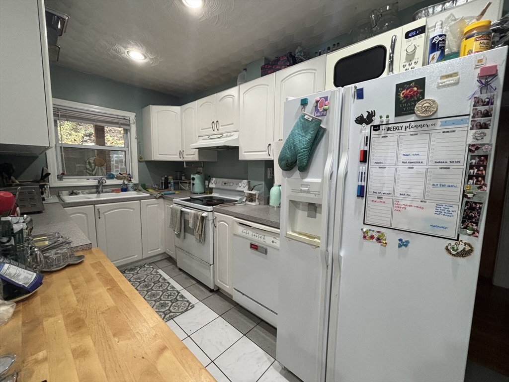 504 Washington Street, Unit 1 Brookline, MA 02446 - Photo 3 of 13 a kitchen with stainless steel appliances a refrigerator a sink and white cabinets