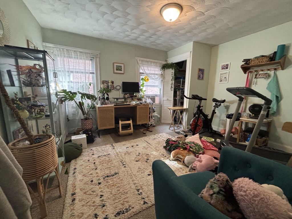 504 Washington Street, Unit 1 Brookline, MA 02446 - Photo 4 of 13 a living room with furniture a window and gym equipment