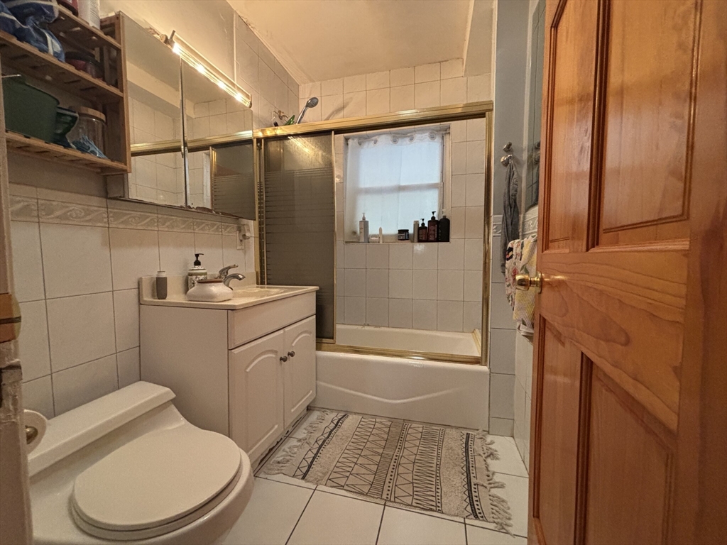504 Washington Street, Unit 1 Brookline, MA 02446 - Photo 7 of 13 a bathroom with a granite countertop sink toilet and shower