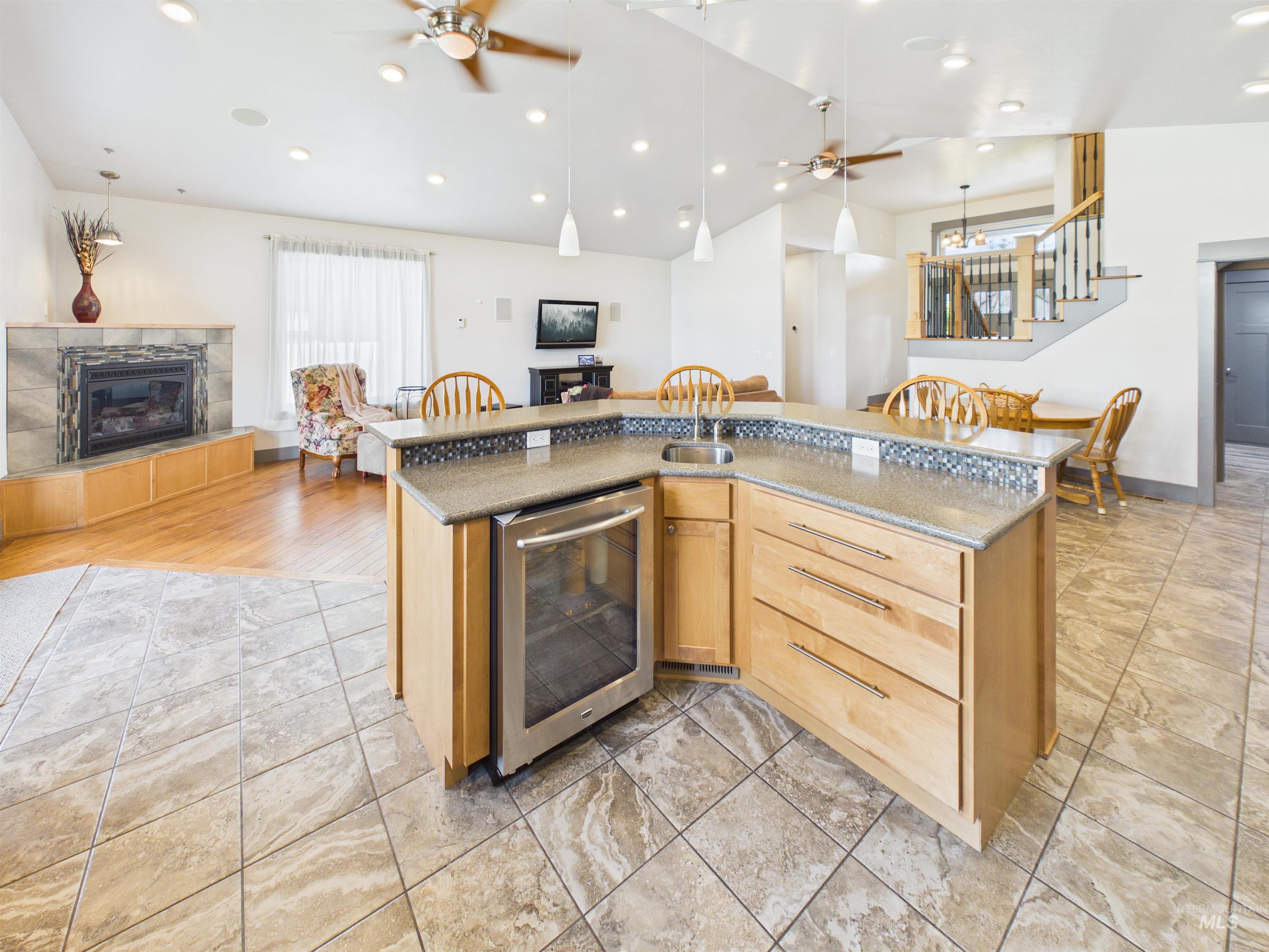 503 Heron Way Rupert, ID 83350 - Photo 48 of 49 Kitchen with a ceiling fan, open floor plan, a tiled fireplace, light wood finish cabinetry, and vaulted ceiling