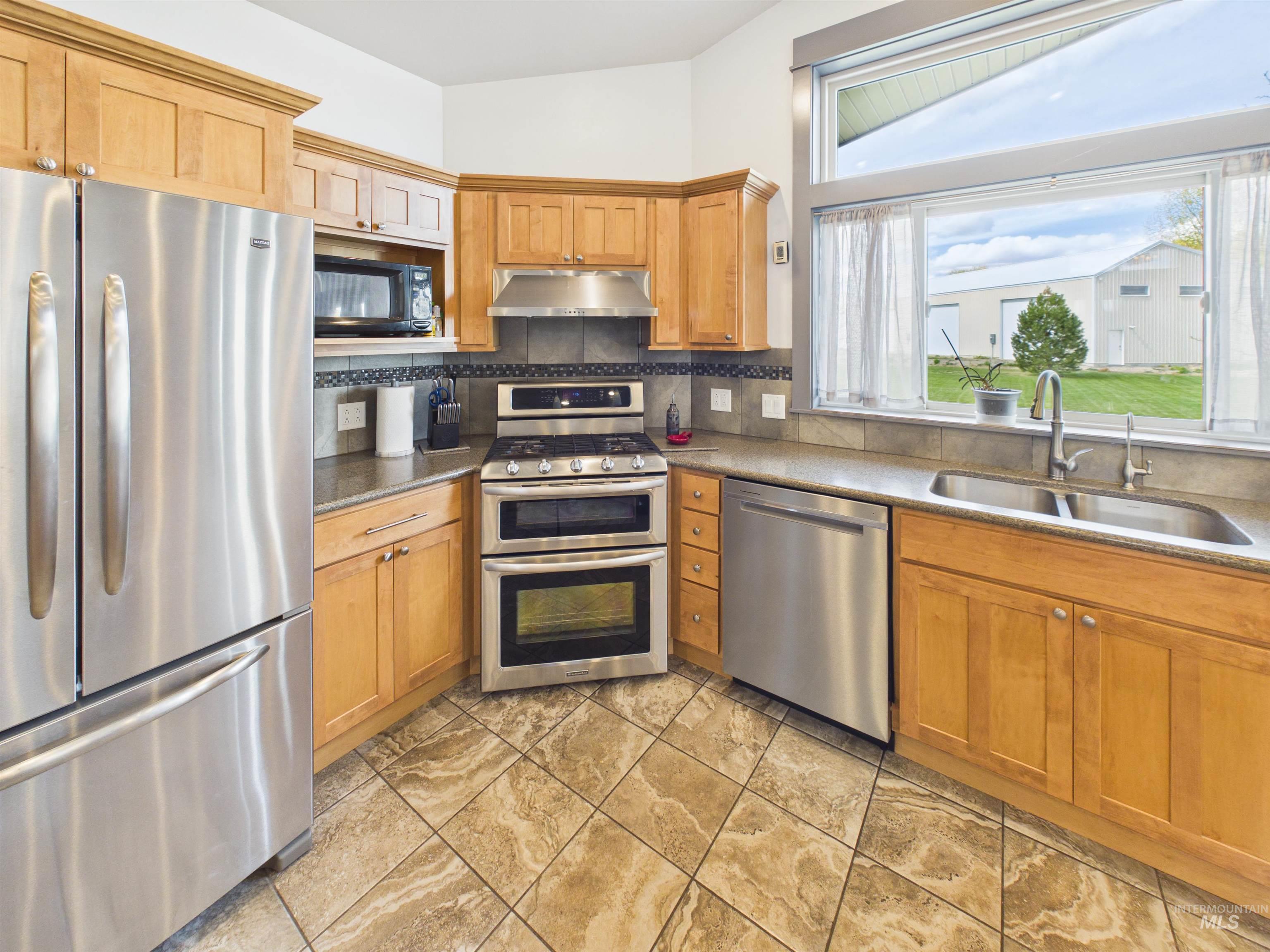 503 Heron Way Rupert, ID 83350 - Photo 12 of 49 Kitchen with stainless steel appliances, decorative backsplash, lofted ceiling, light stone countertops, and wood finish cabinets