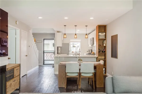 a dining table chairs wooden floor and kitchen view