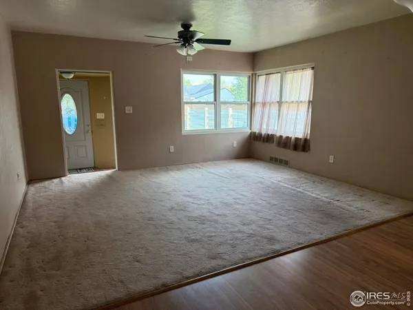 an empty room with windows and ceiling fan