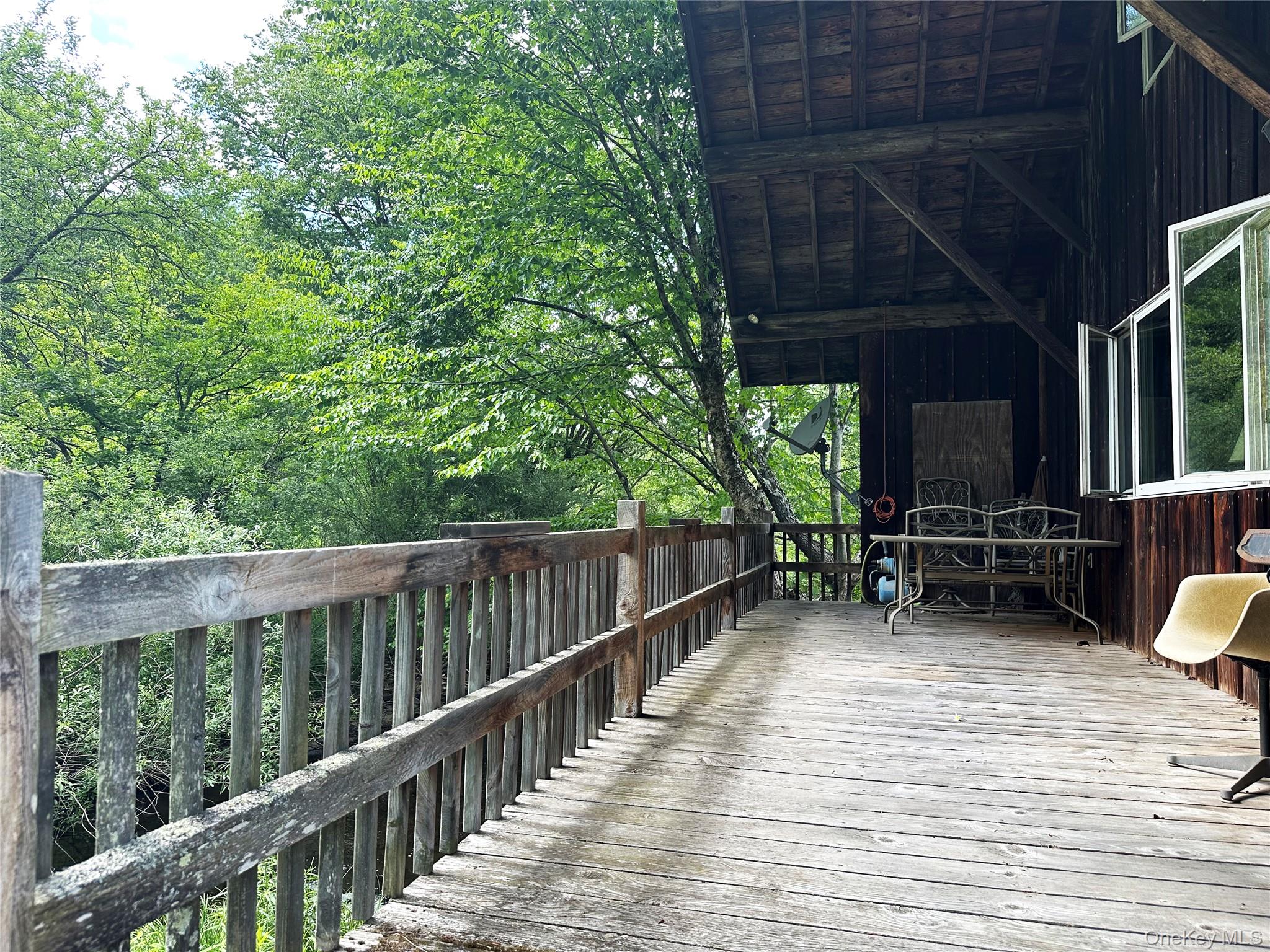 818 Methol Road Roscoe, NY 12776 - Photo 2 of 39 Covered deck positioned directly beside Trout Brook, creating a tranquil outdoor living and entertaining space immersed in nature.