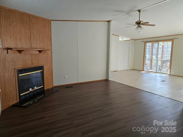 an empty room with wooden floor fireplace and windows