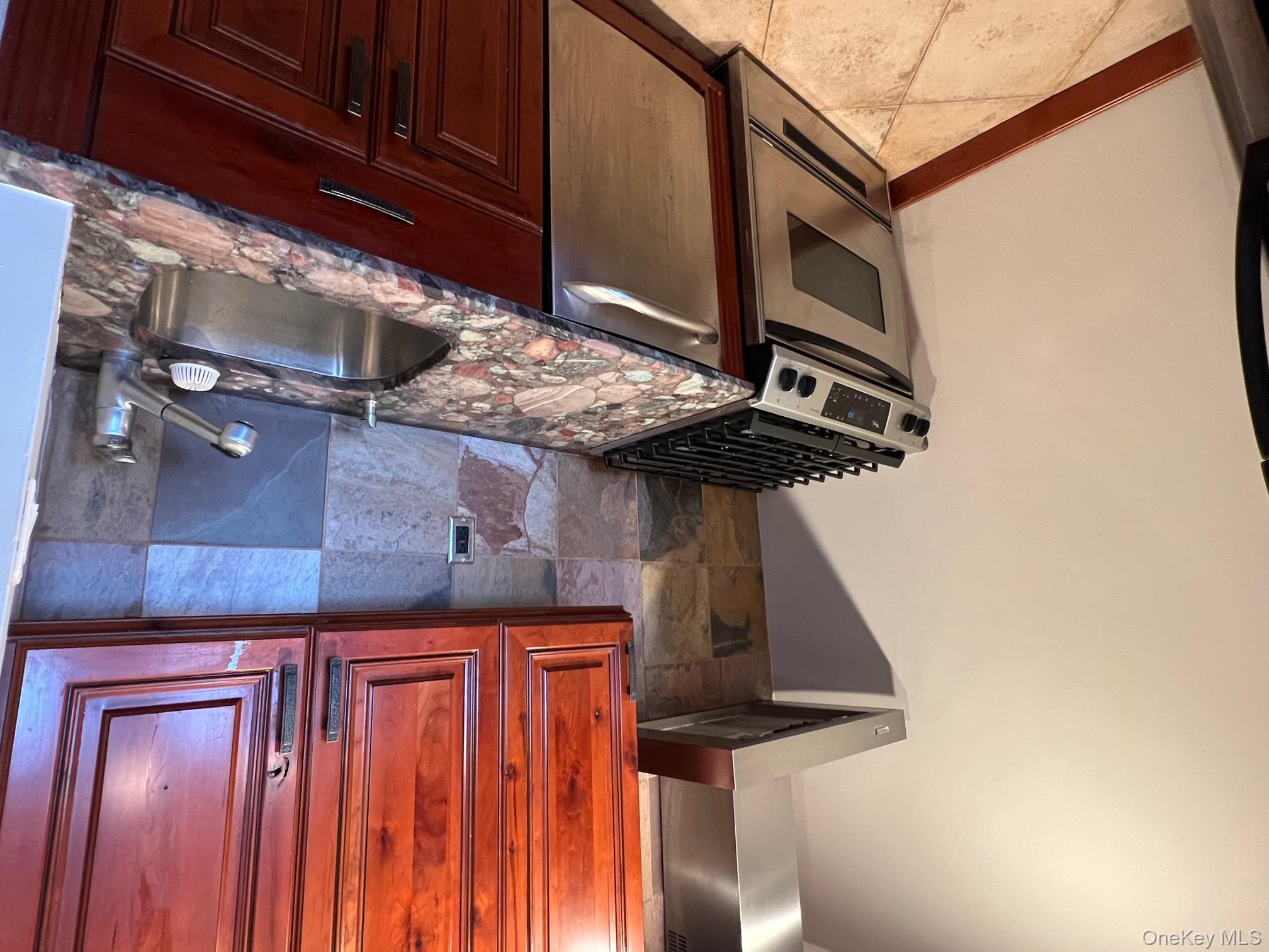 310 Riverside Boulevard, Unit 5H Long Beach, NY 11561 - Photo 4 of 13 a kitchen with granite countertop a sink stove and cabinets