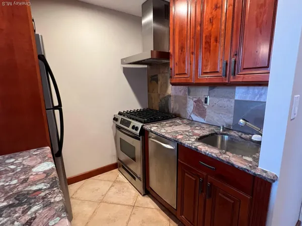 a kitchen with granite countertop wood cabinets and a stove top oven