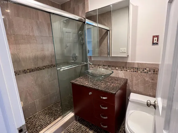 a bathroom with a granite countertop sink a toilet and shower