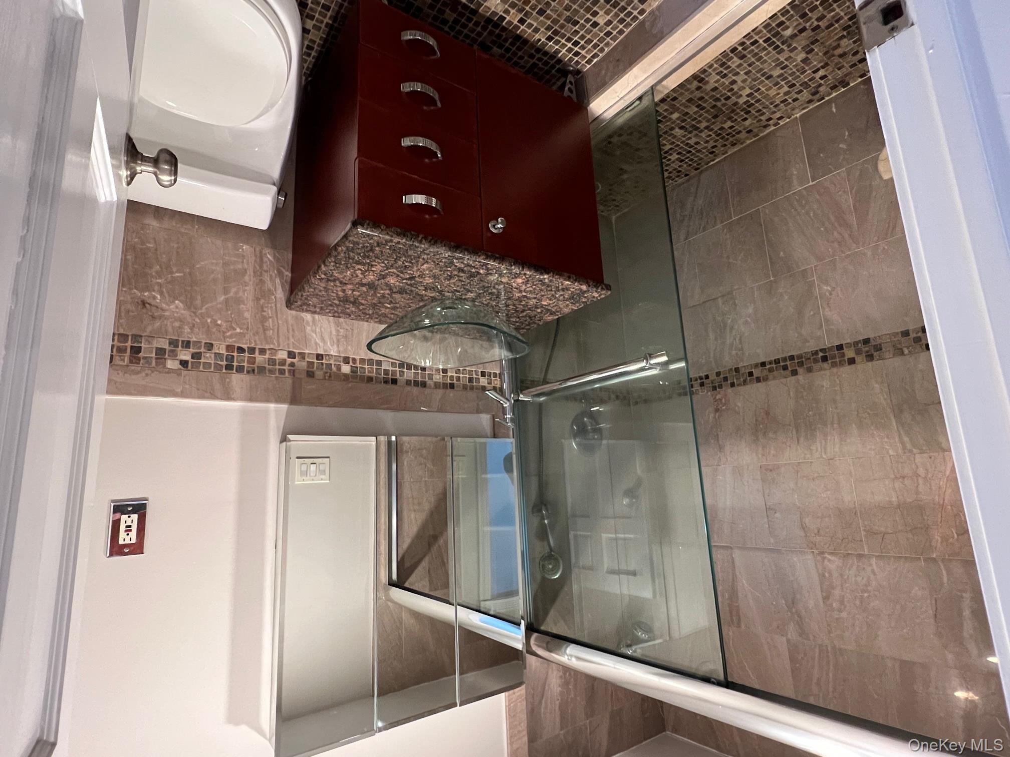 310 Riverside Boulevard, Unit 5H Long Beach, NY 11561 - Photo 9 of 13 a bathroom with a granite countertop sink a toilet and shower