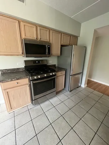 a kitchen with granite countertop a refrigerator and a stove top oven