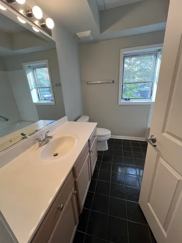 a bathroom with a sink a toilet a mirror and a window