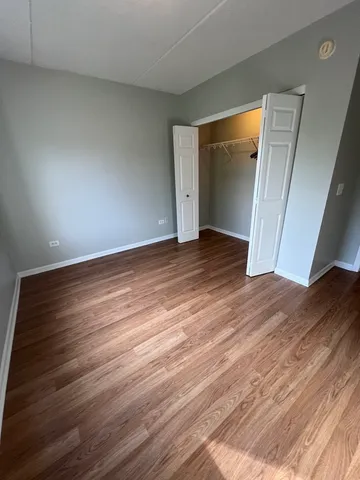 a view of an empty room with wooden floor and closet