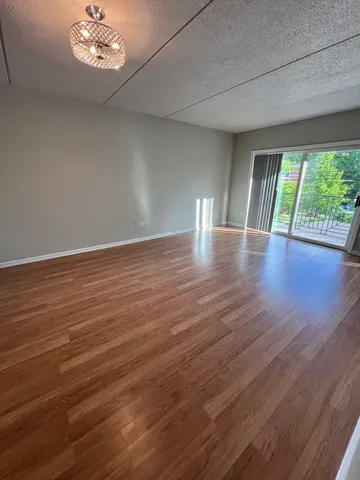 a view of an empty room with wooden floor and a large window