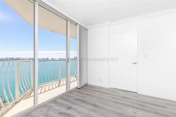 a view of an empty room with wooden floor and windows