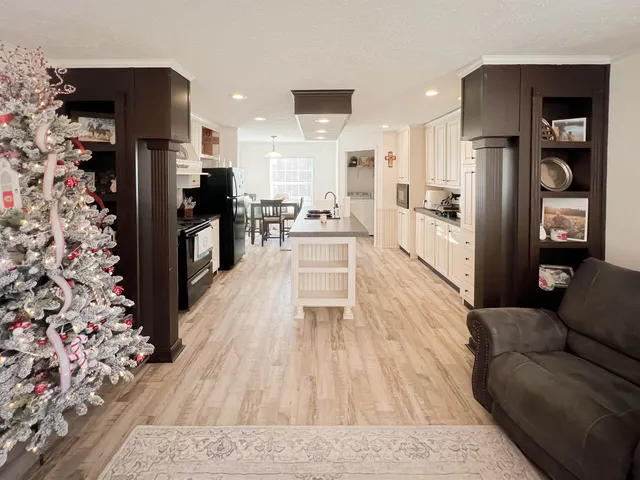 a kitchen with stainless steel appliances a stove a sink a refrigerator white cabinets and wooden floor