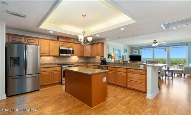 a large kitchen with stainless steel appliances granite countertop a stove top oven a sink dishwasher a dining table and chairs with wooden floor