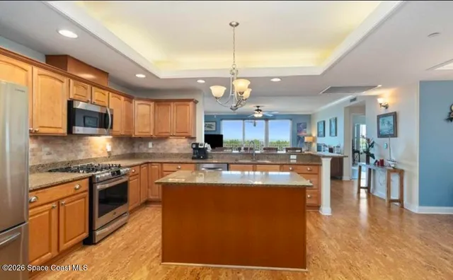a large kitchen with stainless steel appliances kitchen island granite countertop a refrigerator a stove a sink dishwasher and a dining table with wooden floor