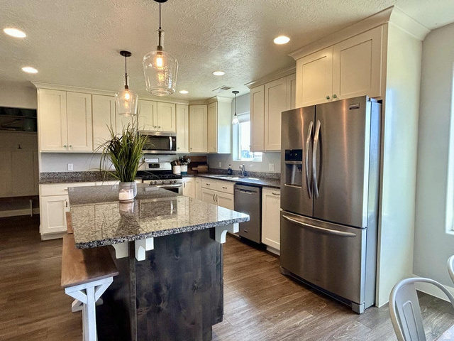310 625 East Enterprise, UT 84725 - Photo 8 of 36 Open-concept kitchen featuring wood-finish flooring, white cabinetry, granite countertops, and stainless steel appliances