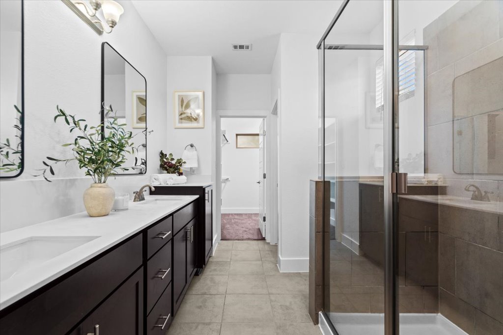 1765 Rowdy Loop, Unit 47 Leander, TX 78641 - Photo 25 of 40 A spacious vanity with dual sinks anchors this modern bathroom featuring a tiled glass shower.