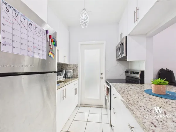 a kitchen with stainless steel appliances a white refrigerator a sink a stove and white cabinets