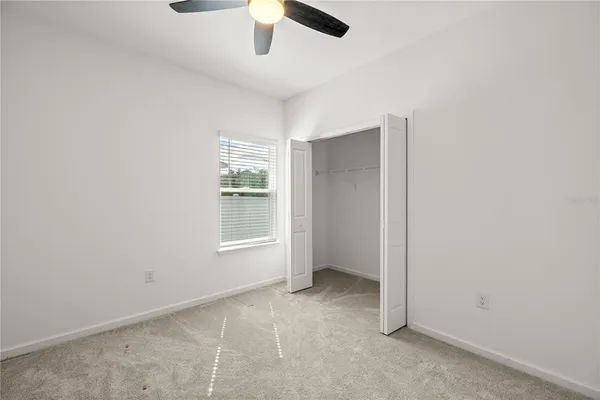 an empty room with a window and a fan