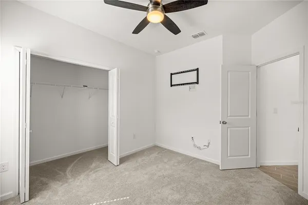 an empty room with closet and a chandelier fan