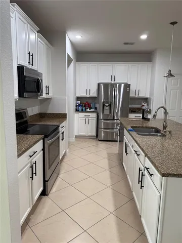 a kitchen with stainless steel appliances granite countertop a stove refrigerator sink and microwave