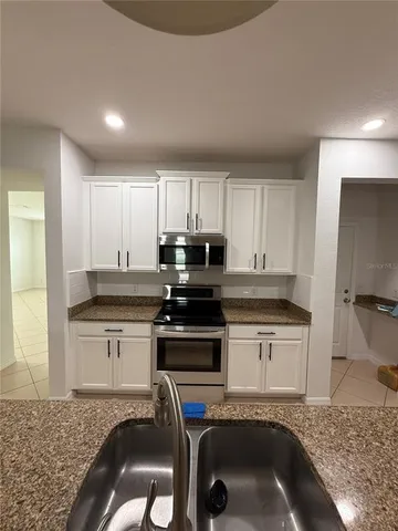 a kitchen with granite countertop a sink stove and cabinets