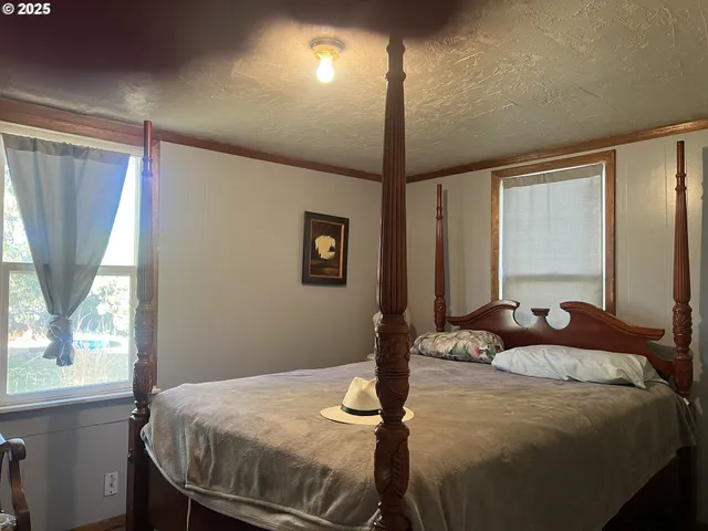 a bedroom with a bed and large windows