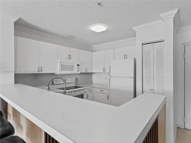 a kitchen filled with white cabinets and white appliances