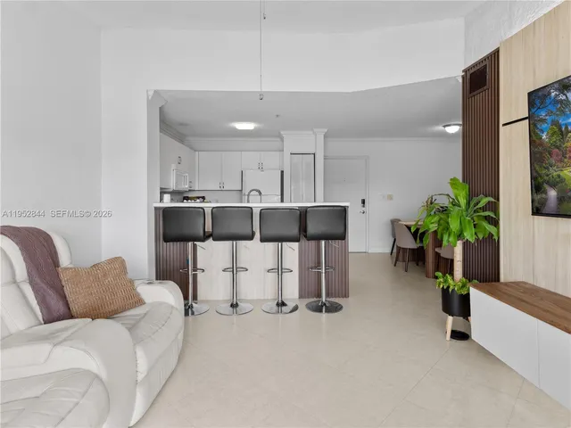 a living room with furniture a potted plant and kitchen view