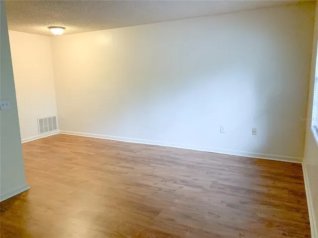 a view of an empty room with wooden floor