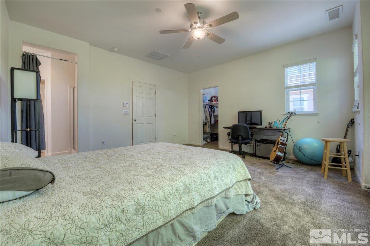 6923 Sacred Circle Sparks, NV 89436 - Photo 17 of 27 a spacious bedroom with a bed and a table in it with window