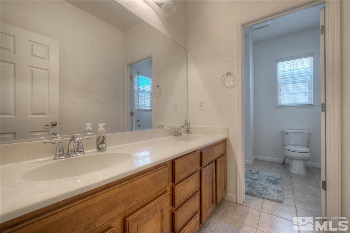 6923 Sacred Circle Sparks, NV 89436 - Photo 22 of 27 a bathroom with a granite countertop sink a toilet and a mirror