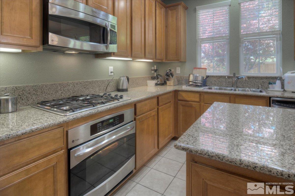 6923 Sacred Circle Sparks, NV 89436 - Photo 6 of 27 a kitchen with stainless steel appliances granite countertop a sink a stove and a microwave