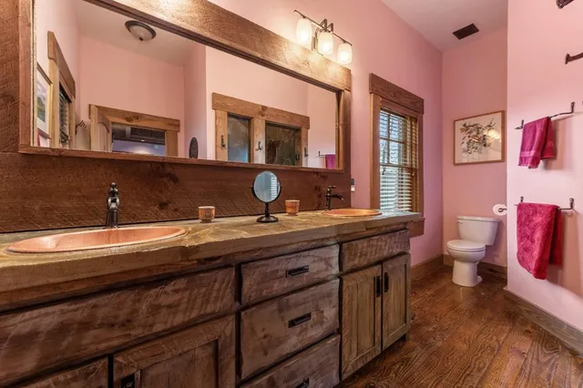 a spacious bathroom with a granite countertop sink a toilet a mirror and shower