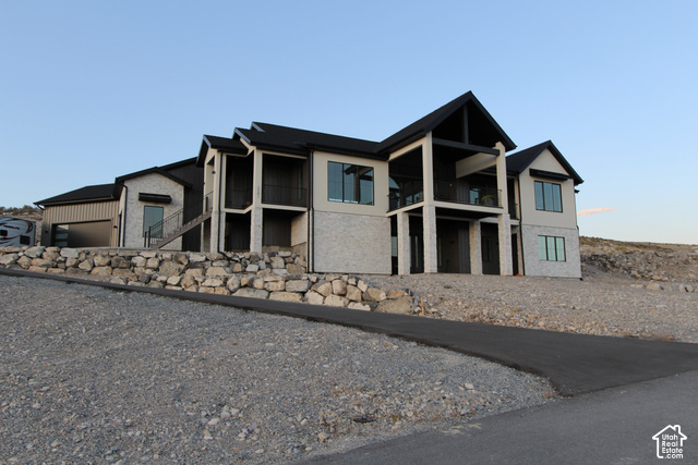 2201 East Unity Way Eagle Mountain, UT 84005 - Photo 1 of 39 Exterior with a mix of light-colored stone and smooth siding, multiple balconies with dark railings, a dark-pitched roofline, and an attached garage with a dark sectional door