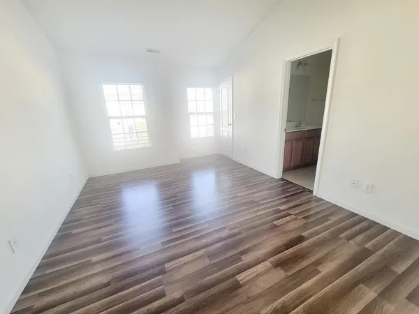 an empty room with wooden floor and windows