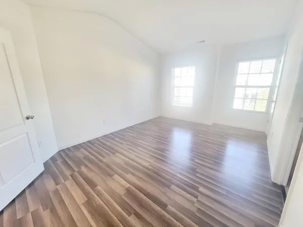 an empty room with wooden floor and windows