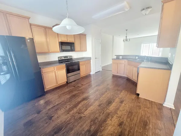 a large kitchen with cabinets wooden floor stainless steel appliances and a window